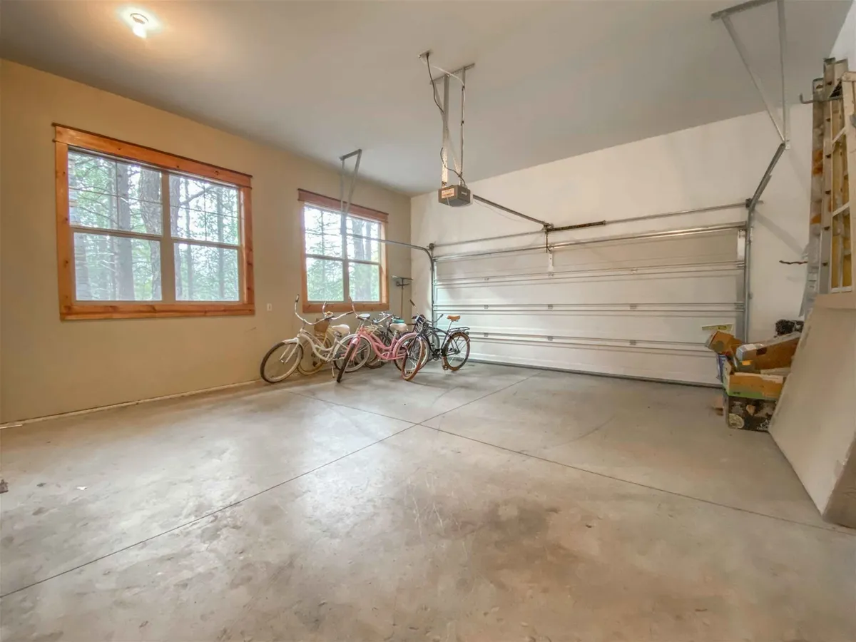 This image shows a garage interior with multiple bicycles arranged neatly, large windows letting in natural light, and a visible garage door. The playful, functional space suggests easy access for family bike outings and showcases a key amenity provided for guest recreation.