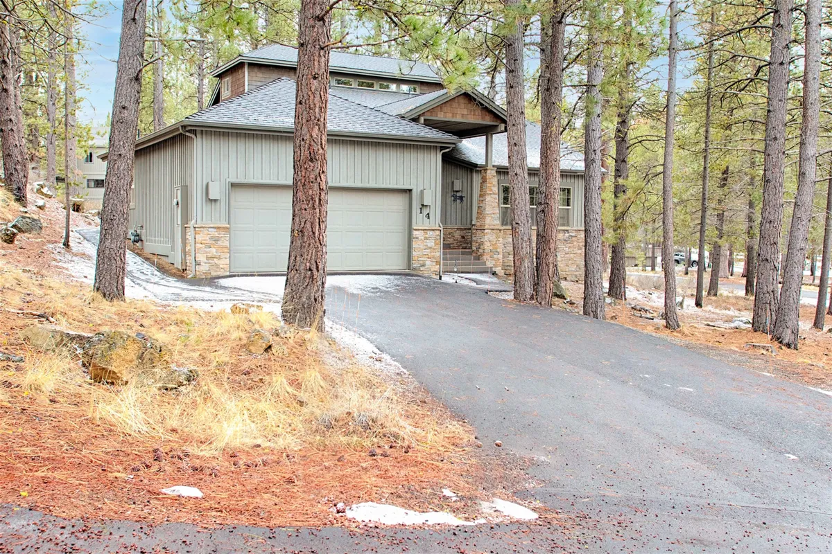 A wide view of the home's modern exterior architecture nestled in its natural surroundings, with a driveway leading to the entrance. The image captures the peaceful, forested setting and hints at the variety of outdoor activities available just steps from the property.
